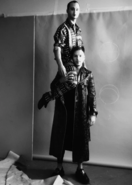 Black and white portrait of two men in a photo studio. One man is carrying the other on his shoulders. Fashion and style.