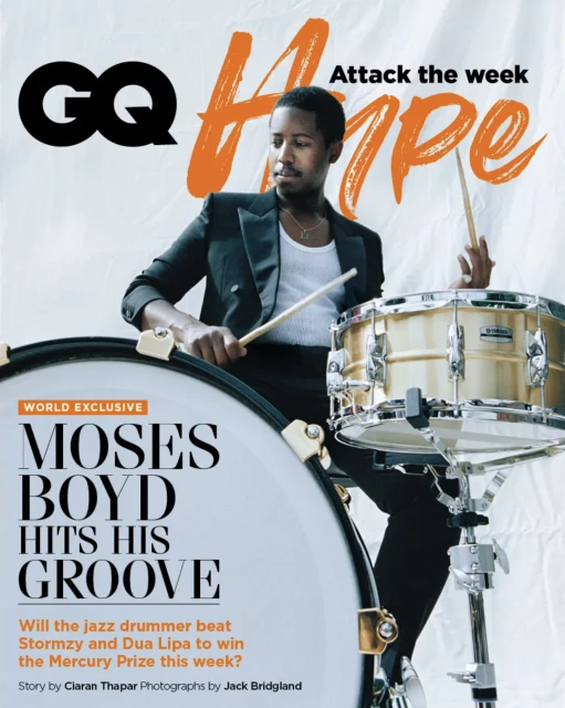 Moses Boyd on GQ cover playing drums. Musician in a black suit jacket holding drumsticks with music magazine's name and headline.
