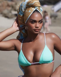 Woman in turquoise bikini top and patterned towel on her head posing outdoors near a sandy beach with natural lighting.