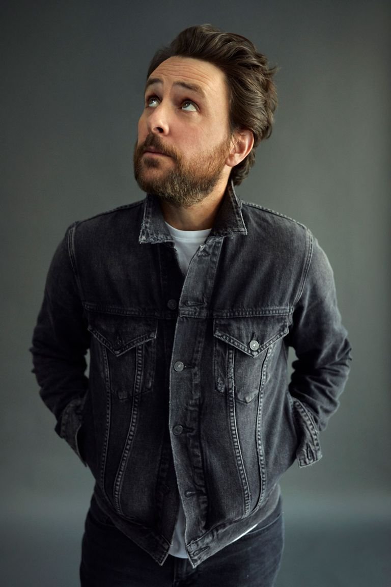 Studio portrait of an adult male with a beard and dark hair wearing a dark denim jacket, gazing upward in a head and shoulder shot.