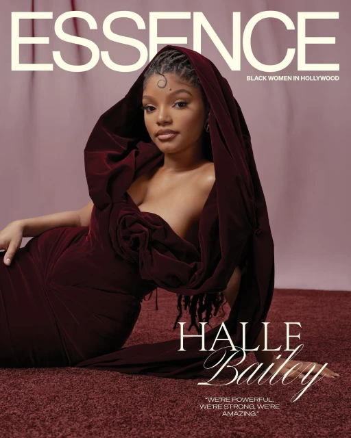 Essence magazine cover featuring Halle Bailey in a dark red gown with a draped hood, lying on a matching dark red surface.