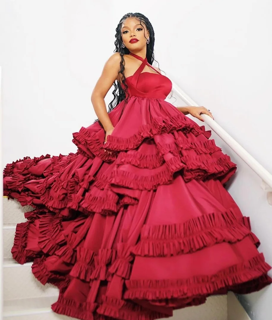 Black woman in a voluminous red ruffled halterneck gown posing on a staircase, styled by Nichole Goodman.