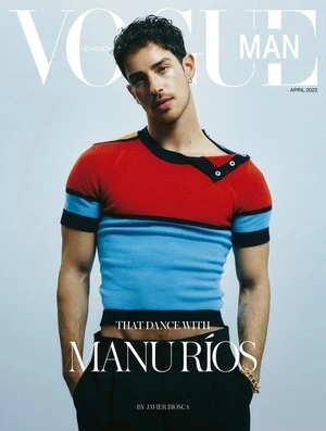 Vogue Man magazine cover featuring model posing in color-blocked sweater, black pants, and gold bracelet against a light blue background.