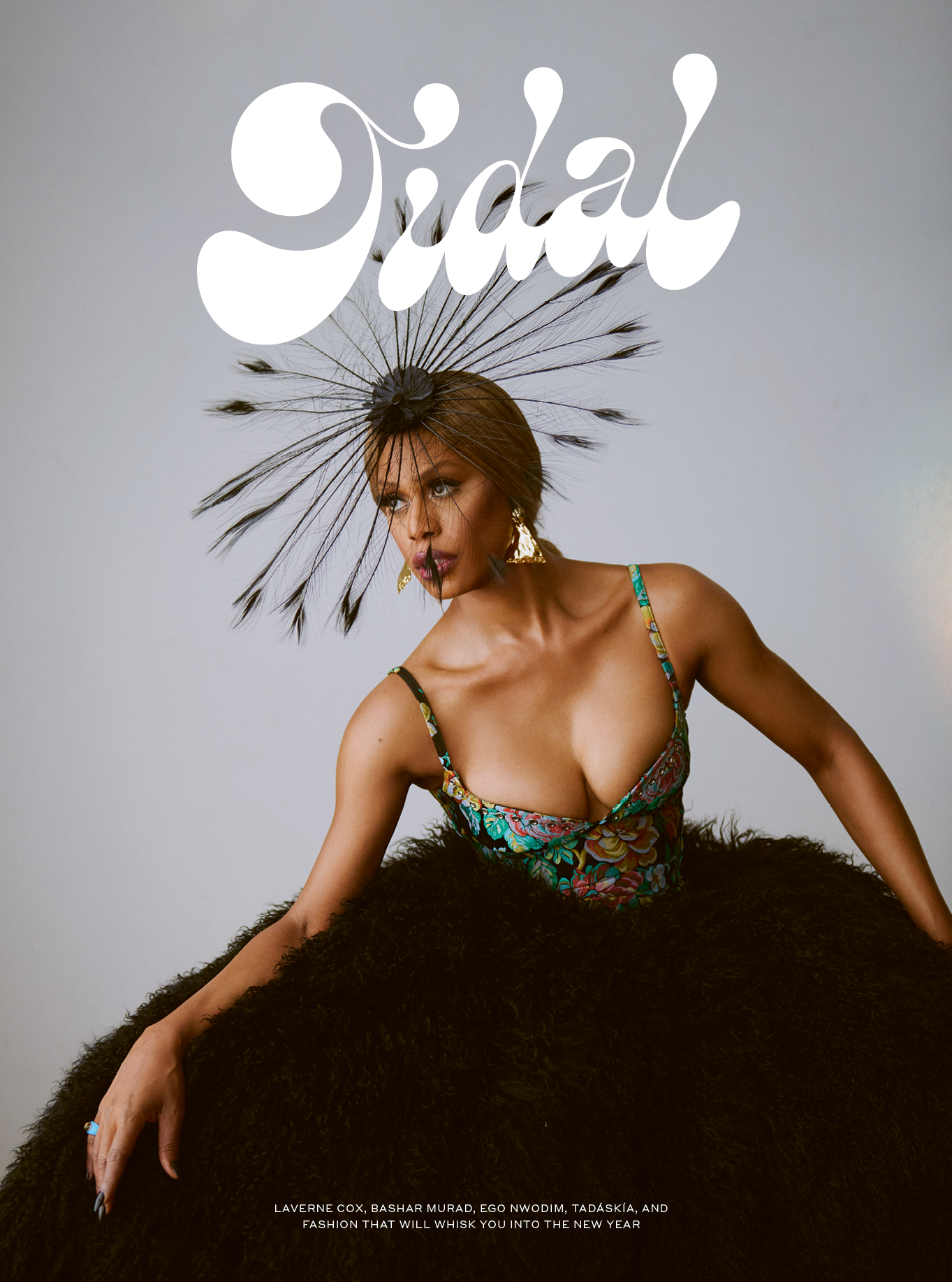 Laverne Cox poses in an extravagant feathered dress and headpiece for Tidal Magazine's cover, set against a neutral studio backdrop.