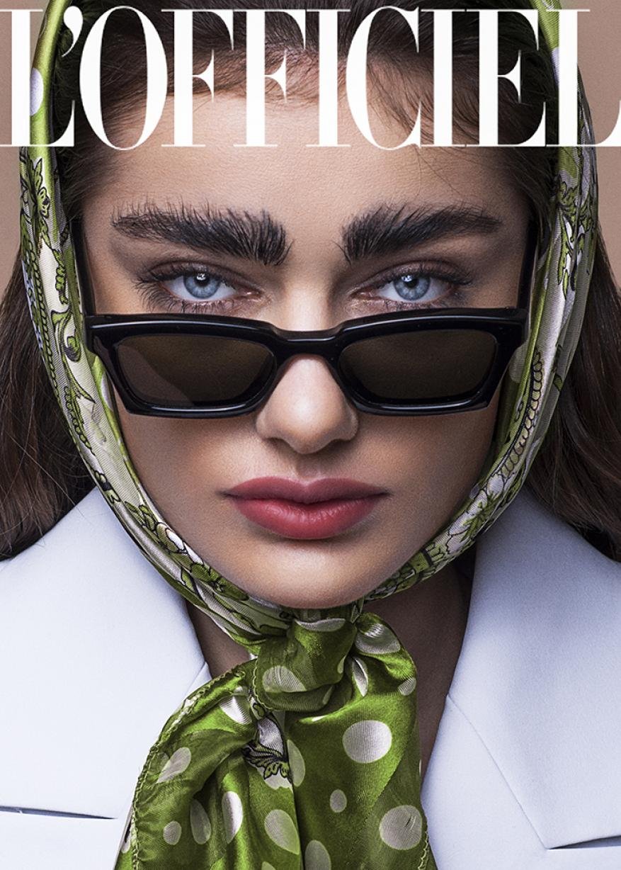 Close-up portrait of a woman wearing sunglasses and a headscarf, against a neutral background, with the magazine title L'Officiel on top.