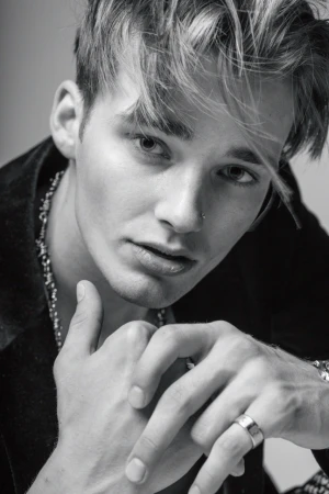 Close-up portrait of a young man with styled blond hair and nose ring wearing a dark shirt, photographed by Parker Burr.