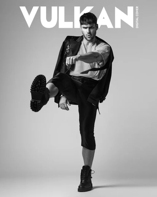 Magazine cover features a fashionable adult male in black jacket and capri pants striking a confident pose against a grey backdrop.