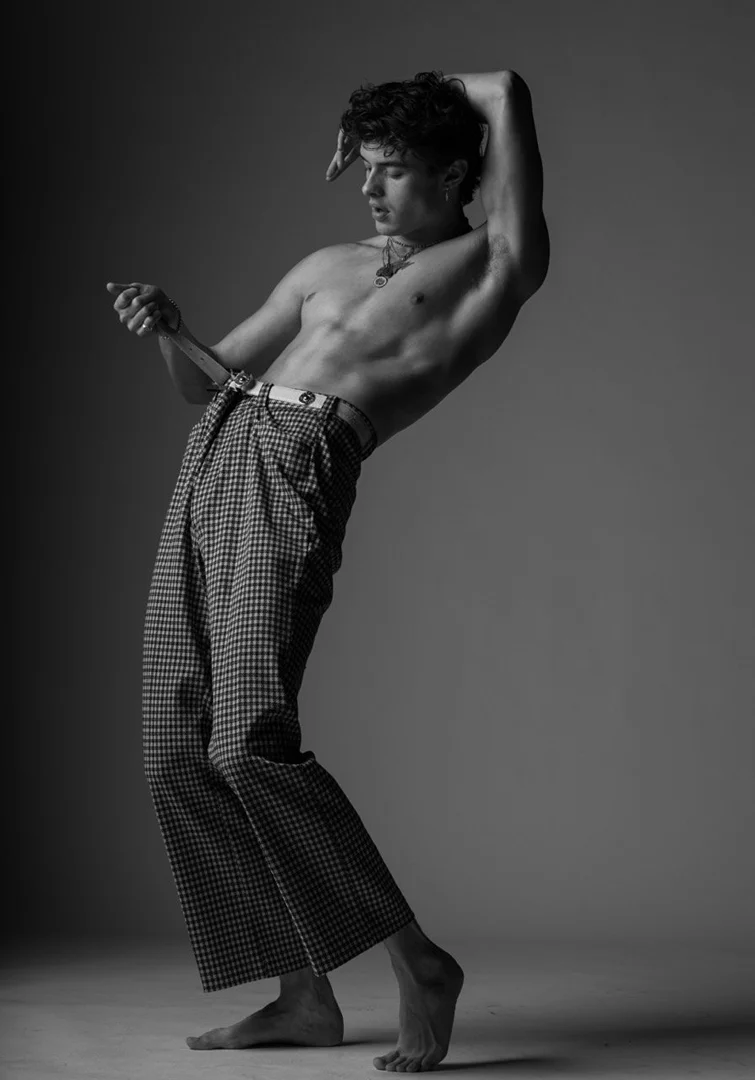 Shirtless man in patterned trousers posing against a grey studio backdrop by Parker Burr