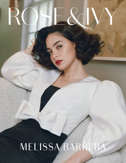 Portrait of Melissa Barrera wearing a black and white dress, posing on a couch, and looking at the camera with a magazine title.