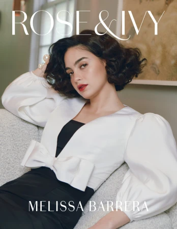 Portrait of Melissa Barrera wearing a black and white dress, posing on a couch, and looking at the camera with a magazine title.