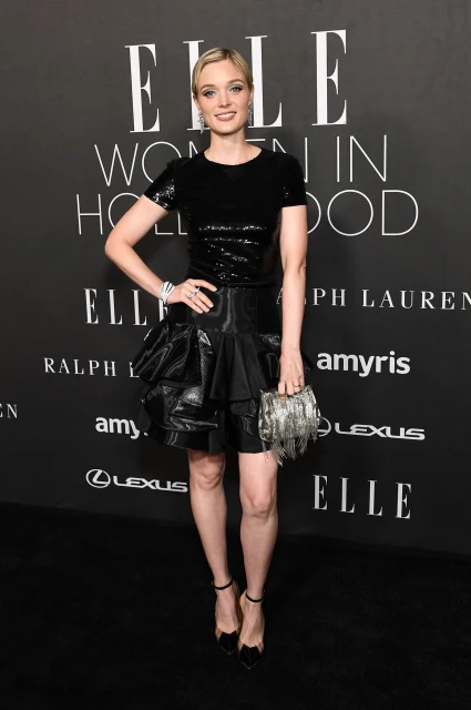 Woman in black sequin top and black skirt attends the Elle Women in Hollywood event, holding a silver clutch purse.