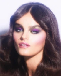 Close-up portrait of a woman with voluminous dark hair and vibrant purple eyeshadow and pink lips by make-up artist Rachel Singer Clark