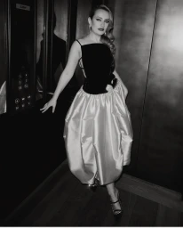 Monochrome portrait of a woman in an evening gown posing in an elevator by photographer Rebecca Spencer