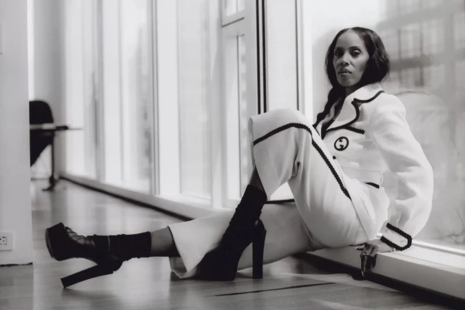Black woman seated near bright windows wearing a white suit with dark trim and platform heels in New York by Renee Sanganoo