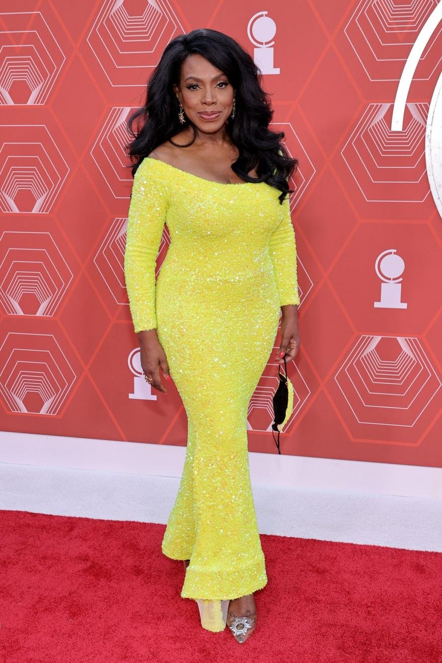 A full shot of Sheryl Lee Ralph in a yellow sequin dress at the 75th Annual Tony Awards, standing on a red carpet in front of a backdrop.