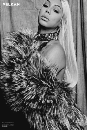 Black and white editorial portrait of a woman wearing a fluffy faux fur coat and a chunky studded choker necklace.