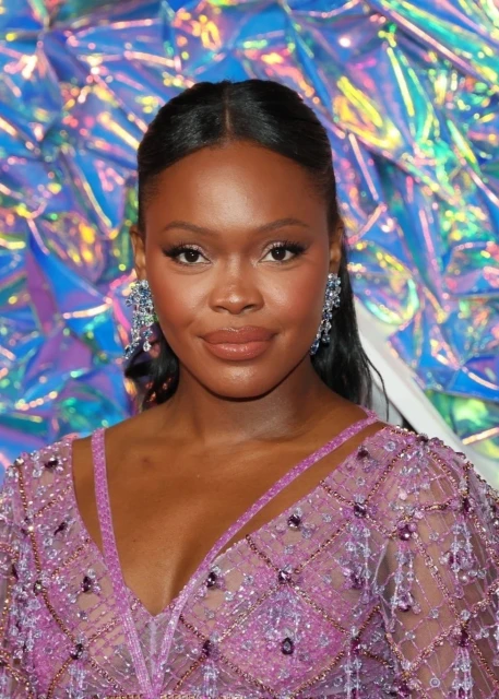 Close-up portrait of an adult woman with dark hair and beaded dress against a colorful background.