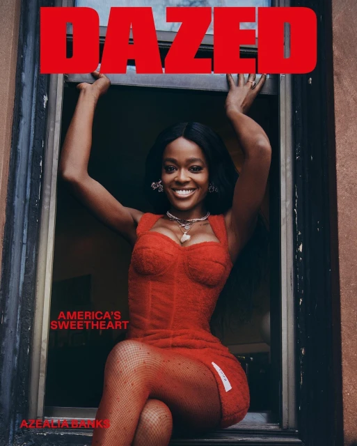 Azealia Banks poses in red dress and matching stockings in a window frame, portrait magazine cover 'Dazed' smiling, indoor lighting.