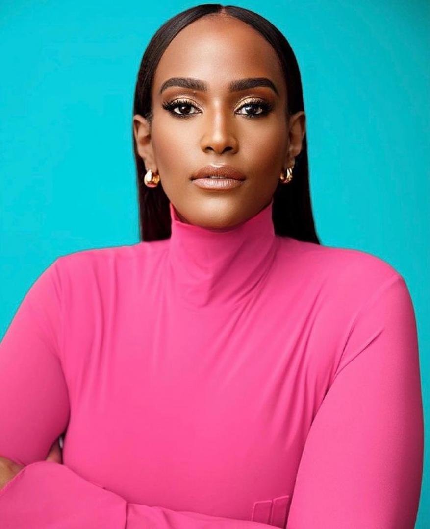 Portrait of a woman with long dark hair wearing a hot pink turtleneck against a bright blue background