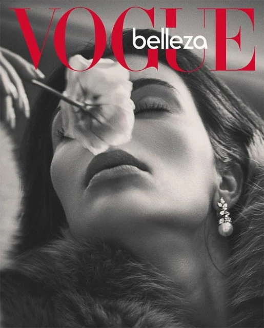 Black and white Vogue cover featuring a woman's face with a white flower over her eye, with a fur collar, and the Vogue logo in red.