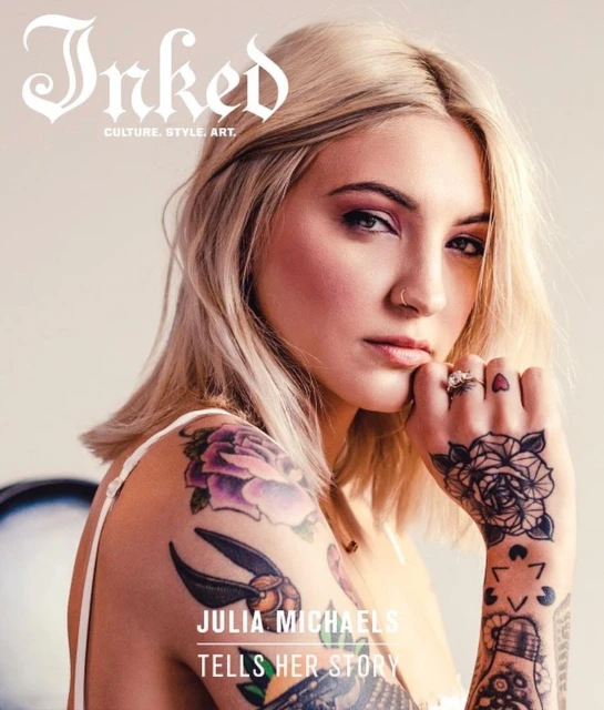 Close-up magazine cover featuring Julia Michaels, a fair-skinned adult woman with blond hair, makeup, piercings, and tattoos on her arms and hands.
