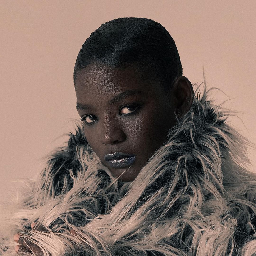Close-up portrait of an African-American woman wearing a fur coat, posing in front of a neutral background. Beauty and fashion concept.