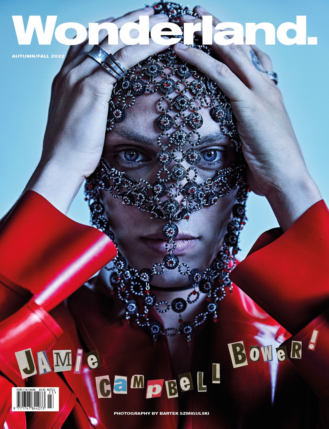 Wonderland Magazine cover featuring Jamie Campbell Bower, adorned with jeweled headpiece, gazing intensely in a close-up shot with a light blue backdrop.