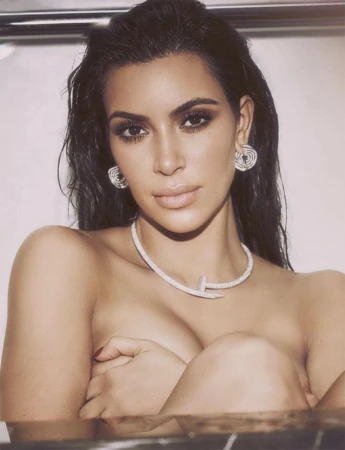 Close-up portrait of Kim Kardashian wearing diamond jewelry and dark smokey eye makeup with wet dark hair.