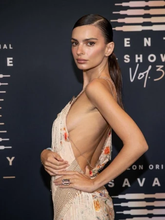 Model Emily Ratajkowski poses in open-backed dress, in a medium studio shot with dramatic lighting at an event for Savage X Fenty.