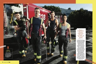 Four male actors dressed as firefighters in dark uniforms with reflective straps walking outdoors with a red fire truck.