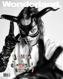 Jamie Campbell Bower wearing a black leather horned mask and gloves for a Wonderland magazine cover portrait.