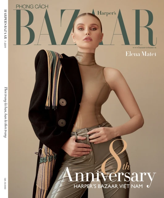 Harper's Bazaar Vietnam cover featuring Elena Matei. Model wears a beige bodysuit and metallic pants, posing with a black coat draped over the shoulder.