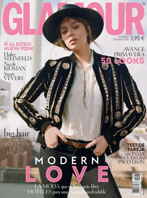 Glamour magazine cover featuring Hailee Steinfeld in a black hat and embellished jacket, with pink Glamour logo and cover text.