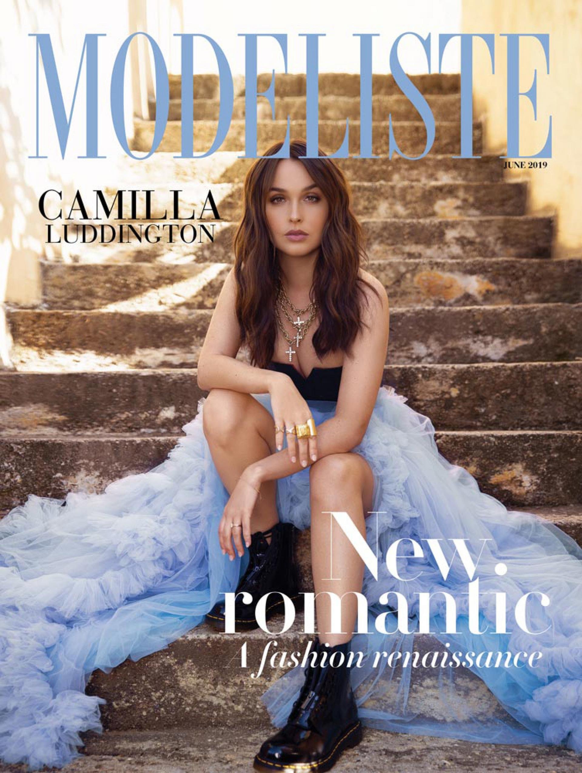 Magazine cover featuring a woman in a black top and light blue dress sitting on weathered stone steps, with magazine text overlay.