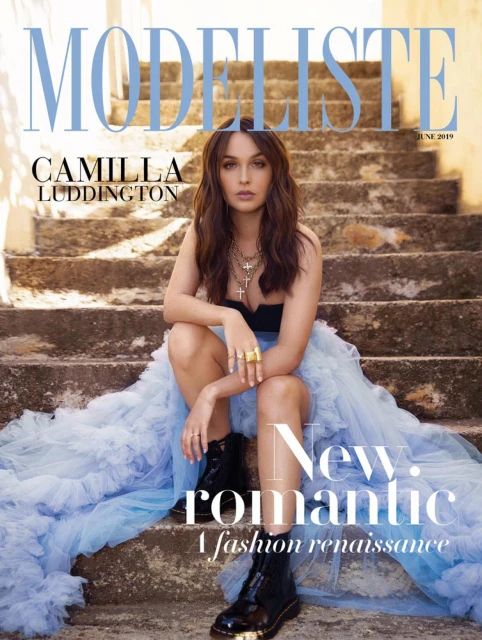 Magazine cover featuring a woman in a black top and light blue dress sitting on weathered stone steps, with magazine text overlay.