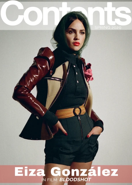 Eiza González on a magazine cover wearing a brown and beige jacket with a black shirt and green headscarf against a gray background.
