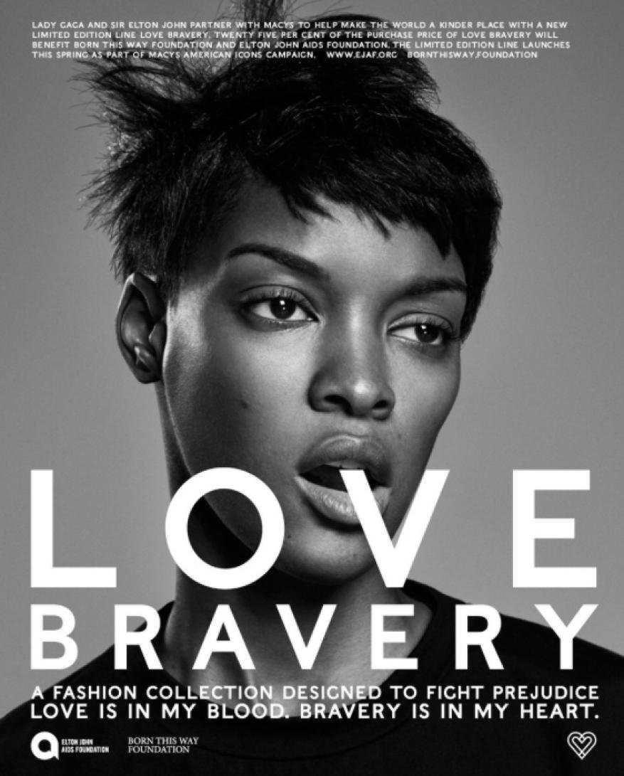 Close-up fashion shot of an African American adult female model wearing a crew-neck shirt, showcasing Love Bravery campaign against gray background.