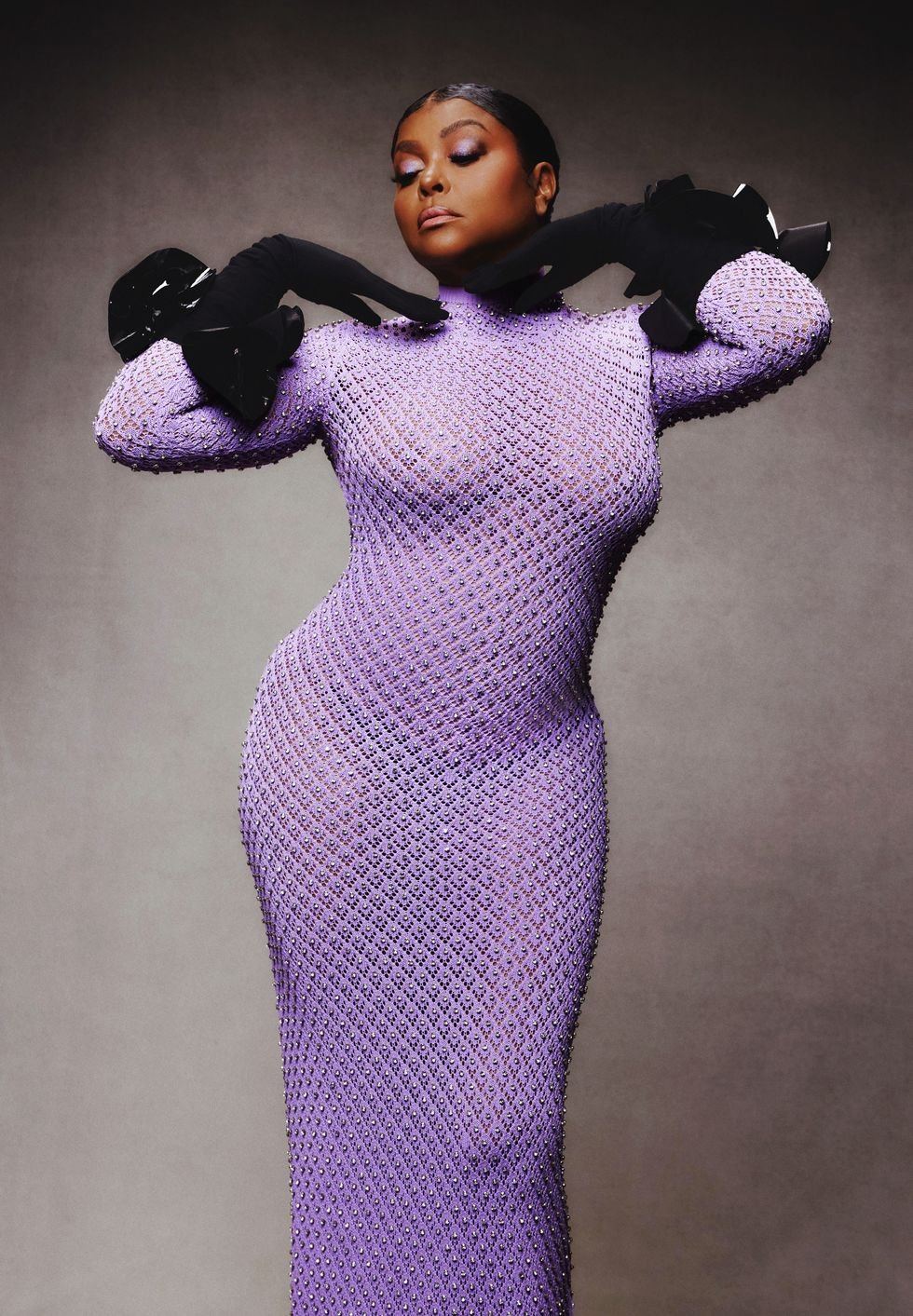 A full-length portrait of an African-American woman wearing a lavender dress with black gloves, posing in front of a grey backdrop.