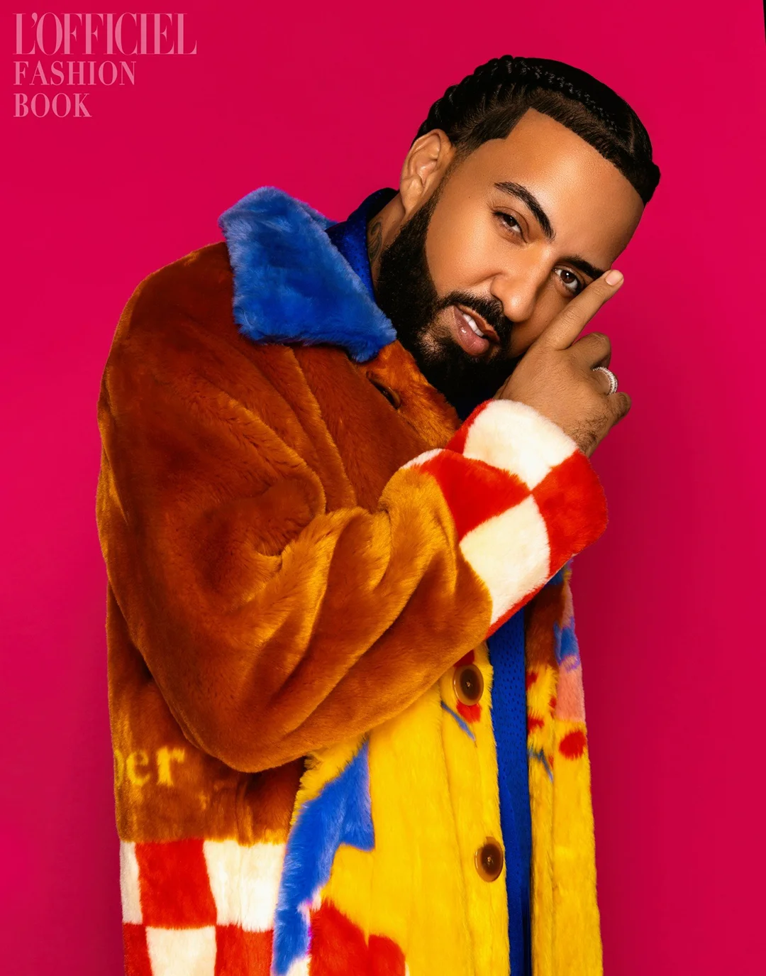 Close-up studio portrait of a stylish bearded man in a colorful faux fur coat against a pink background. Fashion editorial style.