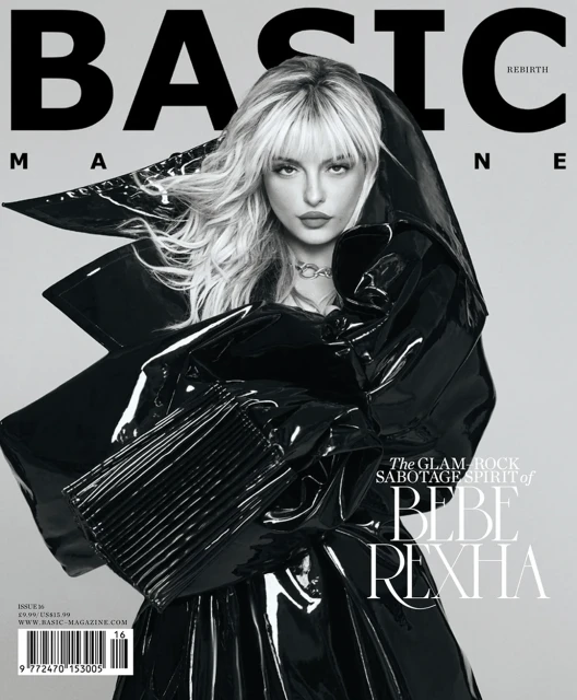 Magazine cover featuring Bebe Rexha wearing a glossy black coat with dramatic shoulders, against a grey background with text overlay.