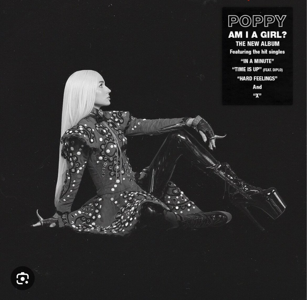 Black and white studio shot of a woman with long white hair wearing a dark dress with light circular patterns and platform boots.