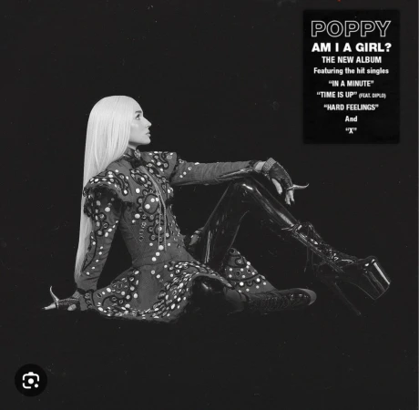 Black and white studio shot of a woman with long white hair wearing a dark dress with light circular patterns and platform boots.