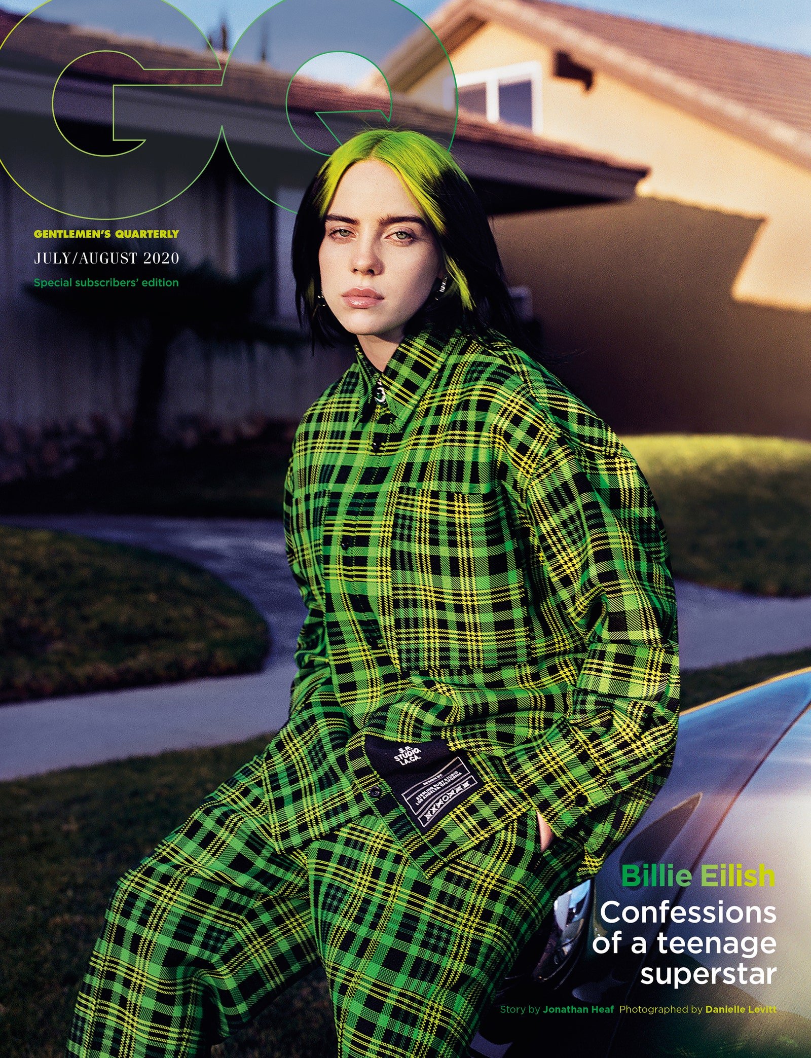 Billie Eilish sits on a car in a green plaid outfit for a GQ cover, with a house and lawn visible in the background, under GQ logo.