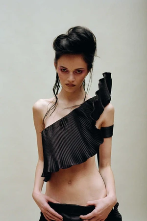 Model in black pleated one-shoulder top with dramatic dark updo hair styled by Samantha Burkhart