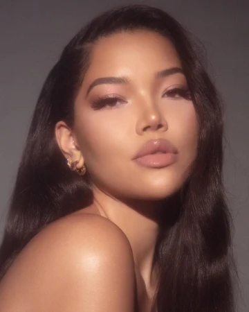Close-up portrait of a woman with dark wavy hair wearing subtle makeup and hoop earrings against a dark neutral background.