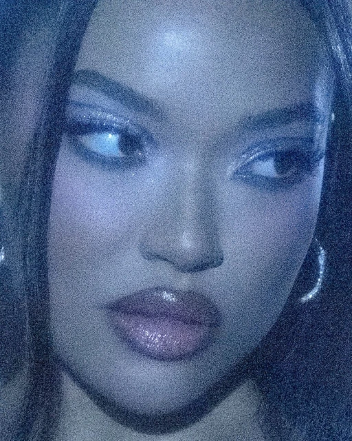 Close-up portrait of a woman with long hair, shiny makeup, and hoop earrings in a blue-toned, grainy aesthetic.