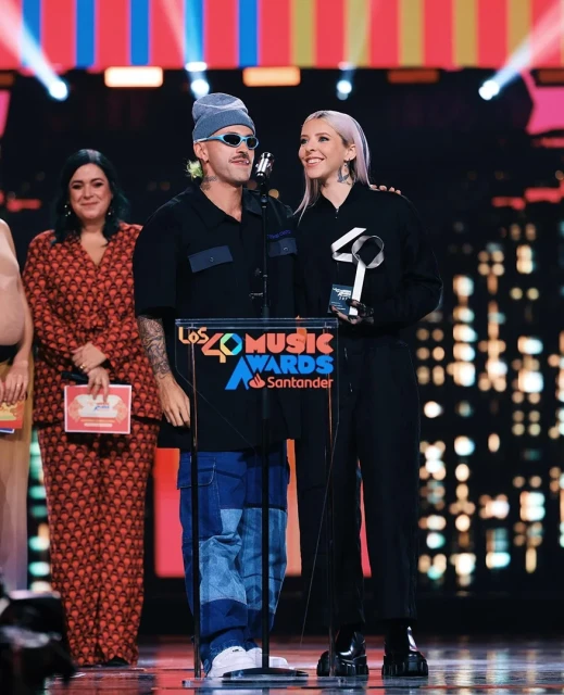 Two music artists on stage accepting an award at 'Los 40 Music Awards' with audience and award sponsor Santander visible.