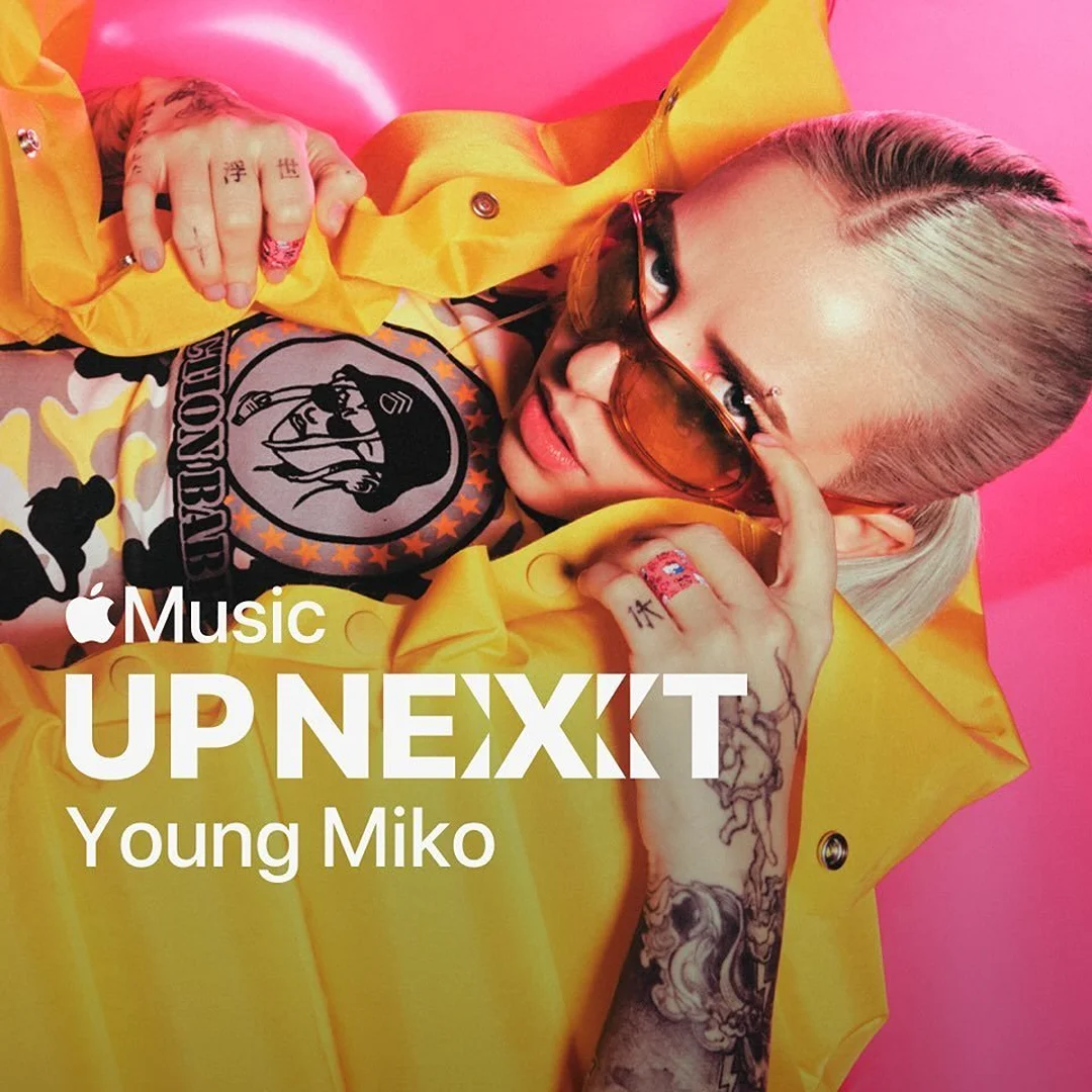 Young Miko is featured on the 'Up Next' Apple Music promotional cover, wearing a yellow jacket and sunglasses against a pink backdrop.