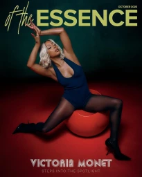 Victoria Monet posing dynamically on a red sphere against a dark green backdrop in a magazine cover styled by Timothy Luke