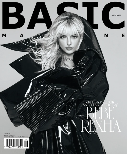 Magazine cover featuring Bebe Rexha in a black patent-leather hooded outfit. Her blond hair is styled with bangs. The background is grey.